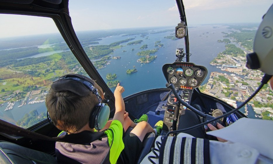A child points down at the St. Lawrence River as he sits in a helicopter.
