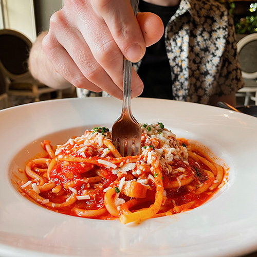 A hand twirls a fork filled with spaghetti.