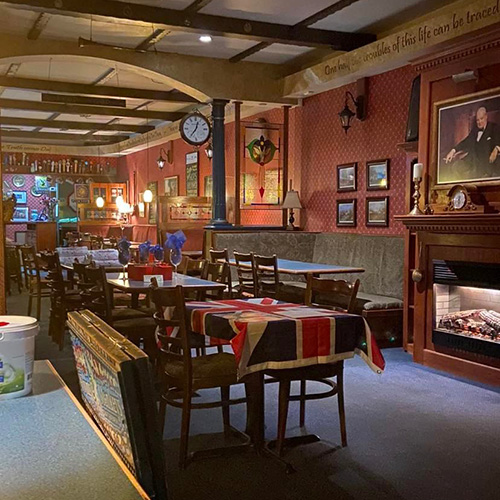 The interior of a pub, with red walls and a collection of tables.