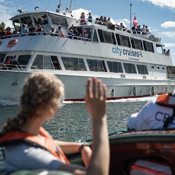 A person waves at a tour boat on the St. Lawrence River.