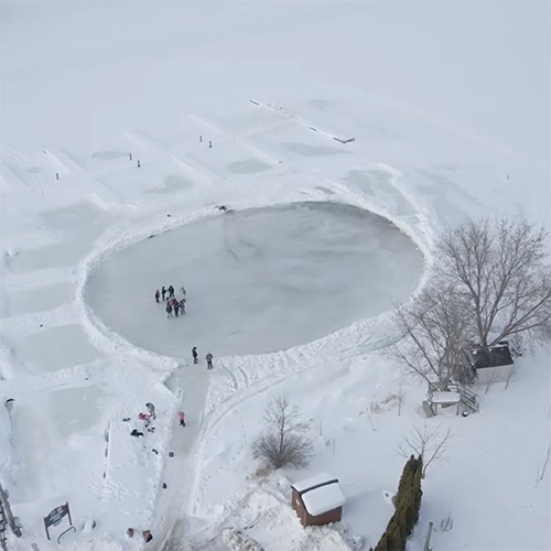 A frozen pond with a group of skaters.