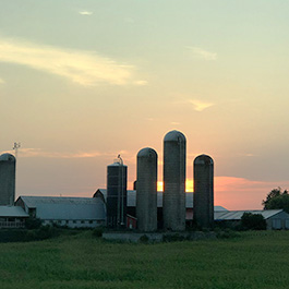 A farm as the sun sets behind it.